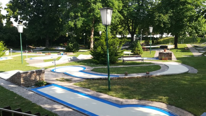 Minigolf course with several courses and trees in the background.